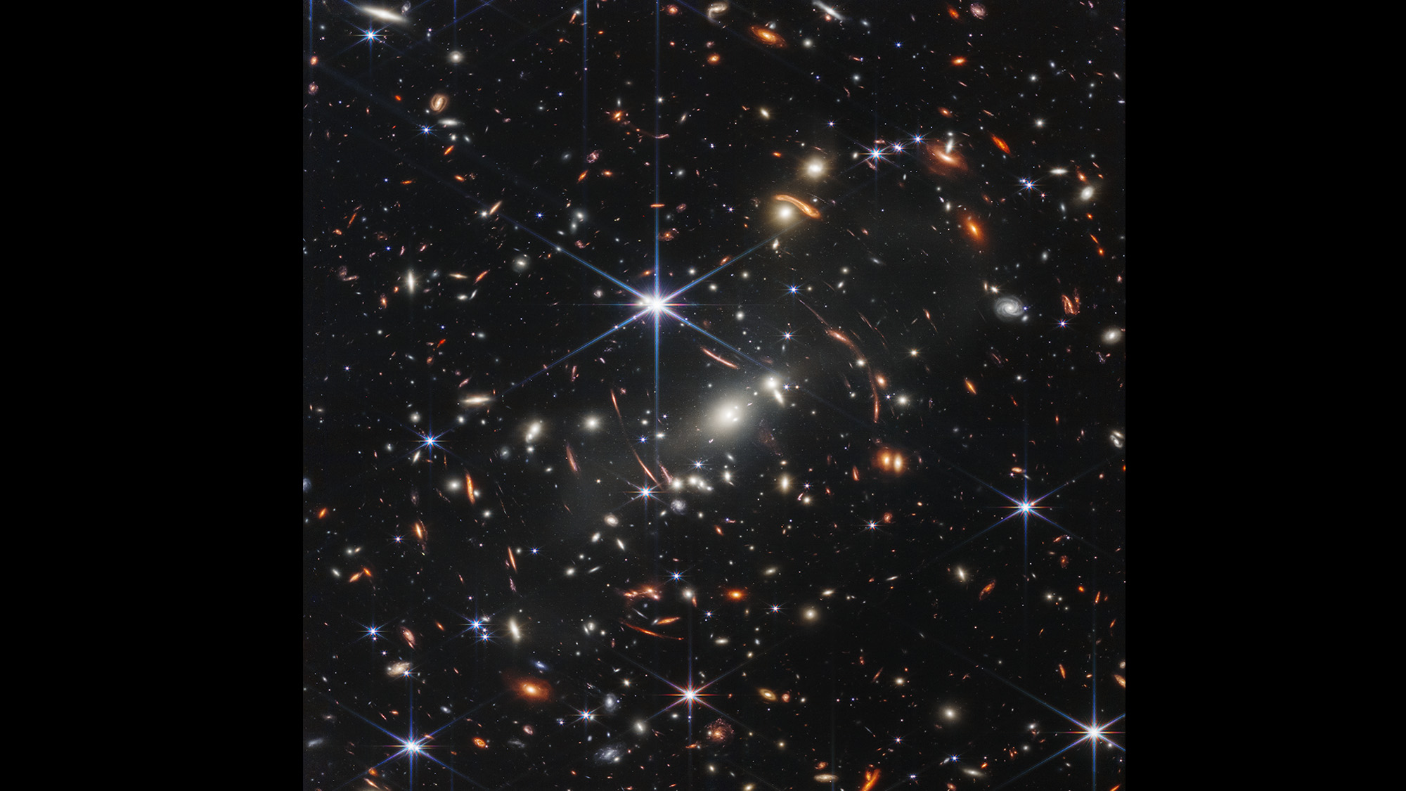 Photo of numerous galaxies scattered across the black void of space.