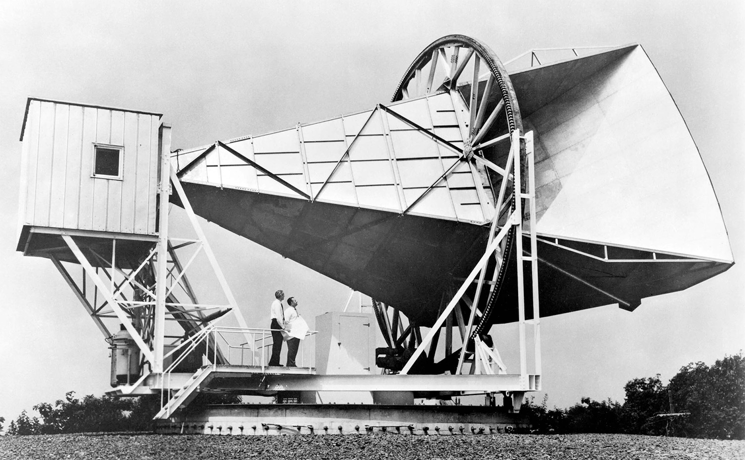 Black and white photo of the Holmdel Horn Antenna in a grass field.