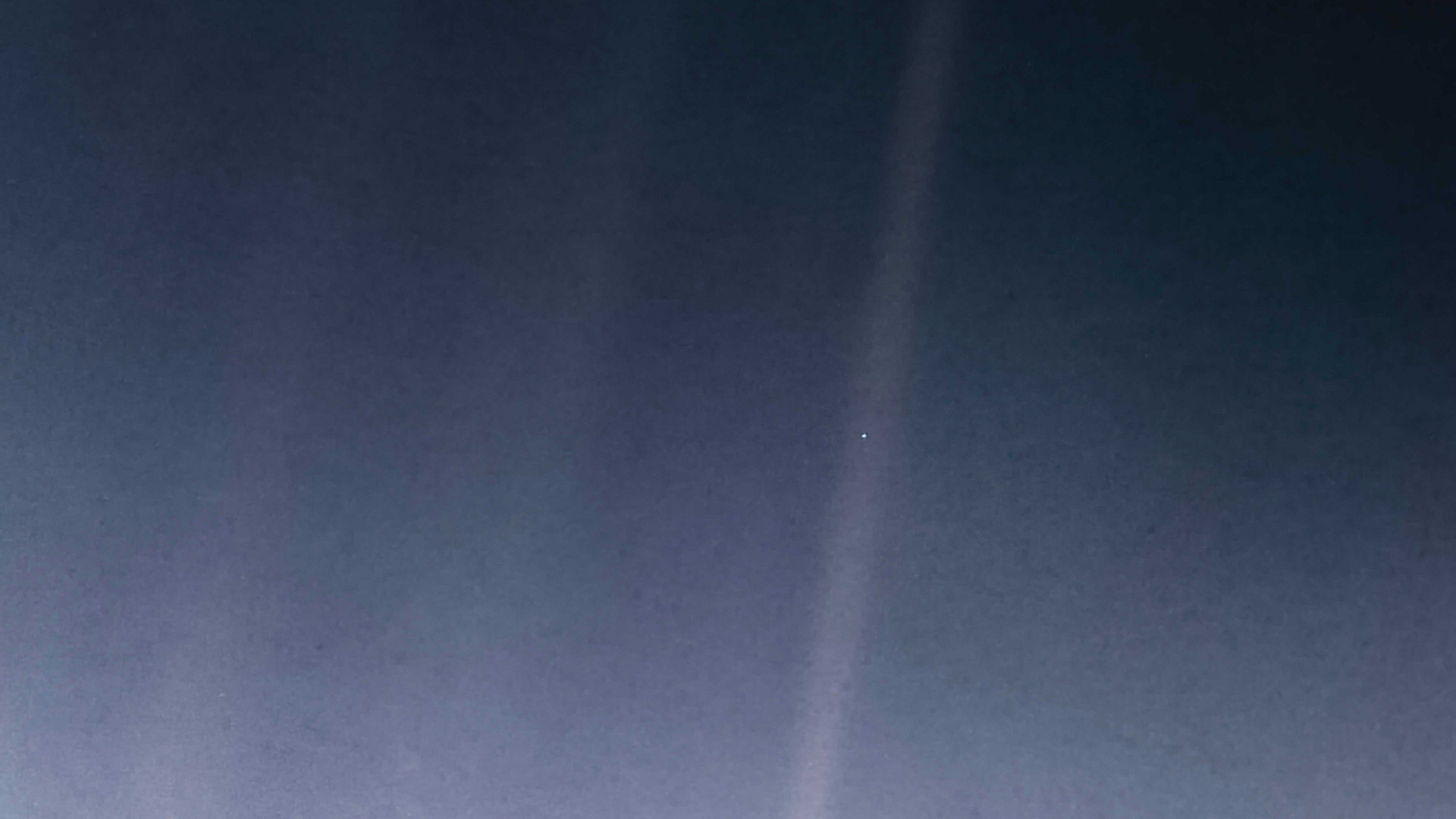 Blue and grey expanse of space with a vertical beam of light, centered is the Earth represented by a tiny white pixel.