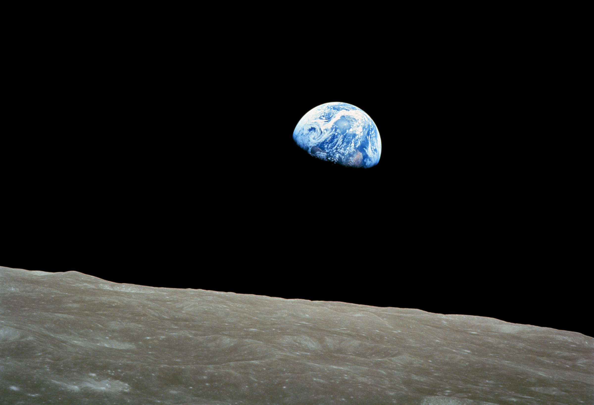Earth against the black void of space, rising above the moon.